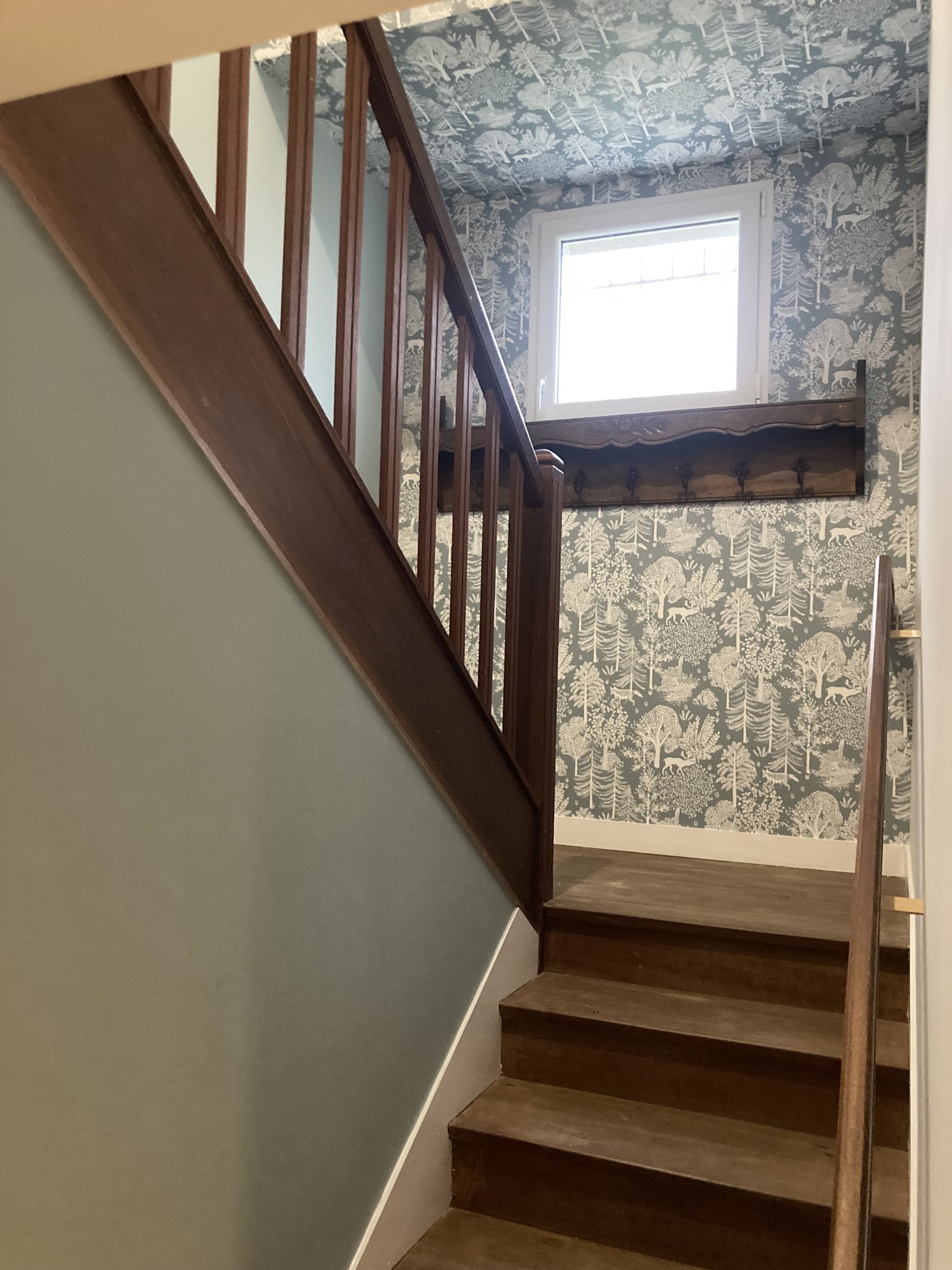 Cage d'escalier rénovée avec papier peint bleu motif paysage